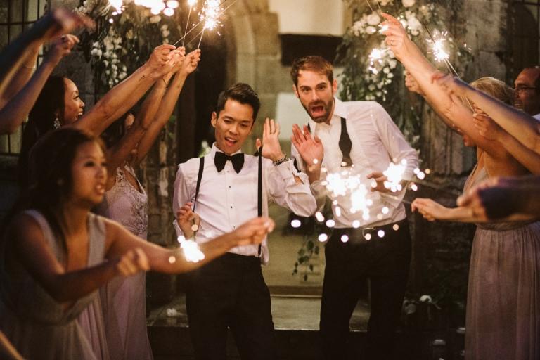 Berkeley Castle Wedding - two grooms dance as their wedding party hold sparklers