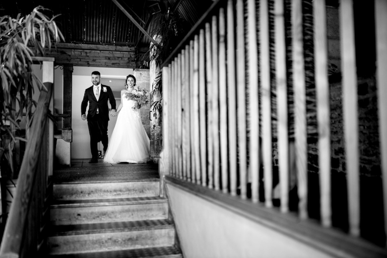 Couple walk into wedding breakfast at stone barn