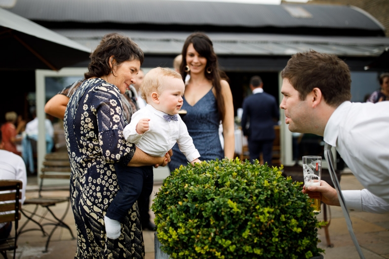 Dad makes faces at his baby at wedding at Cripps stone barn