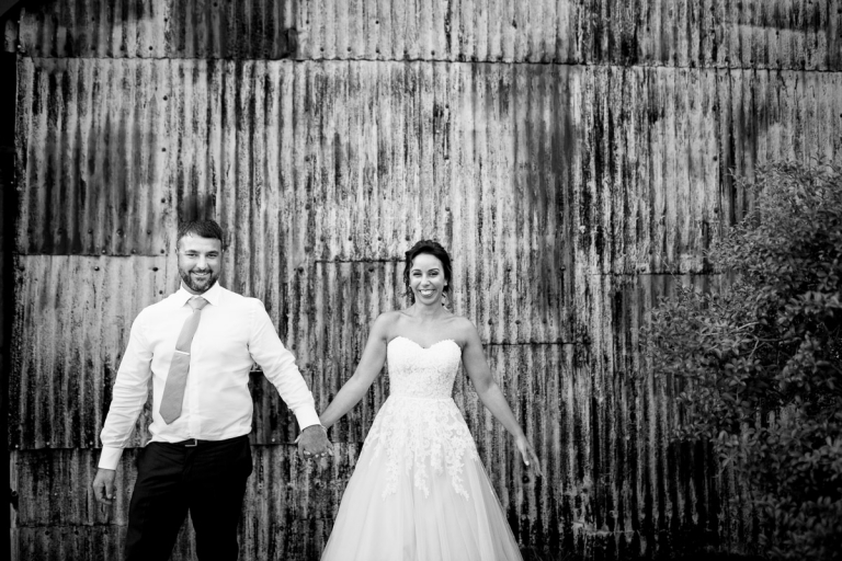 black and white photo of couple in front of corrugated iron exterior of cripps stone barn