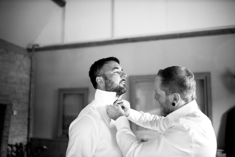 Groomsman helping Groom get ready