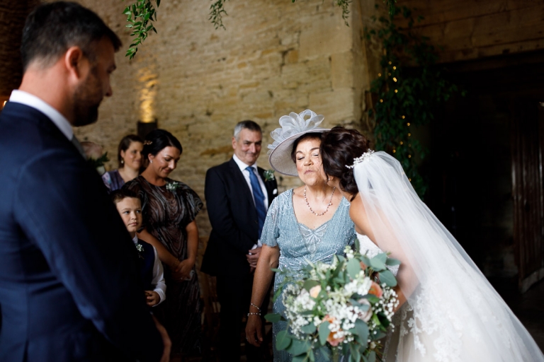 Bride kisses Mum in light blue mother of the bride outfit as she gives her away at Stone Barn wedding