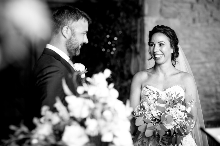 bride looks at groom during ceremony at stone barn