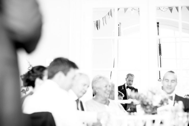 best man reflection in the mirrored walls in the orangery at goldney hall as he gives his speech 