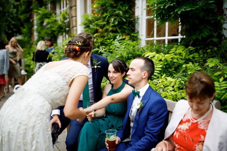 bridesmaid holds the hand of the bride as she tells her something intimate outside the orangery