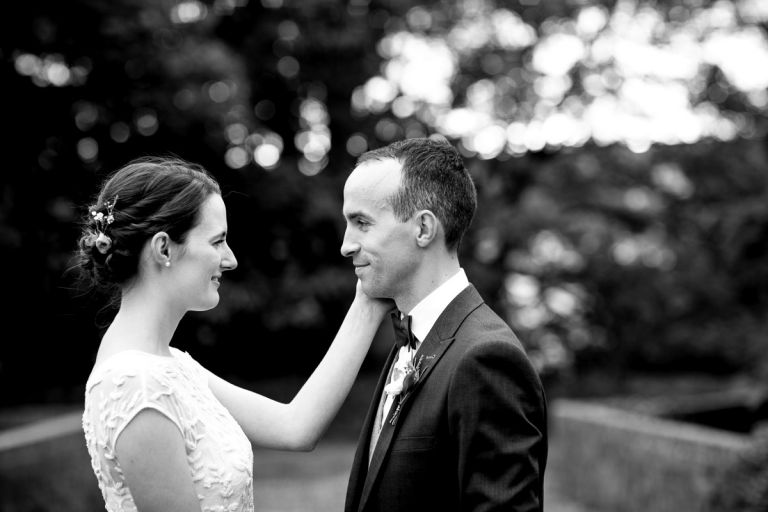 bride puts her hand up to her grooms face and he smiles back at her, intimacy without posing in bristol