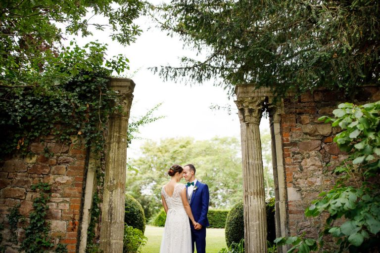 Couple rest their heads together for a photo in the columns outside at goldney hall