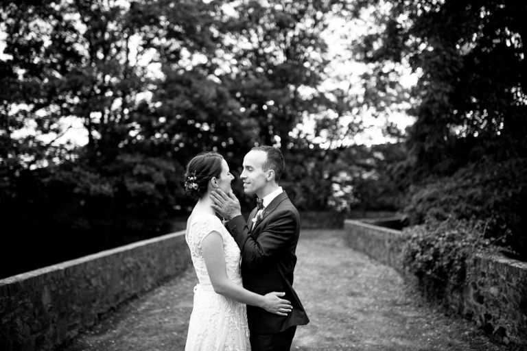 groom holds his wifes head in his hand as he goes to kiss her outside at goldney house