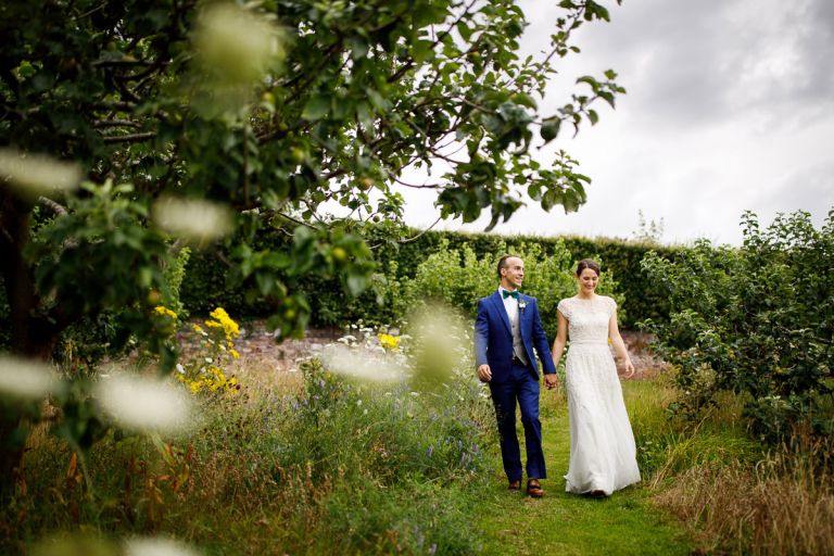 Couple walk surrounded by flowers and trees in the walls of the city garden in bristol