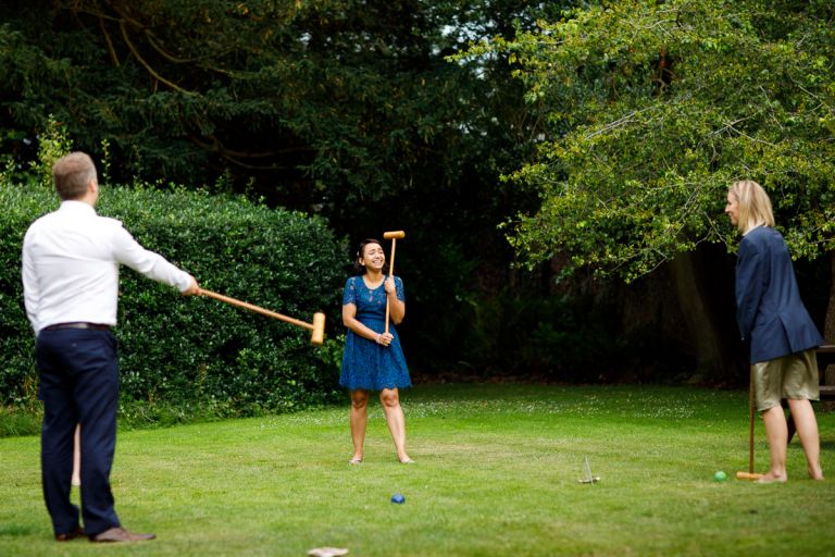 Guest laughs as she plays crochet at a wedding outside at goldney hall