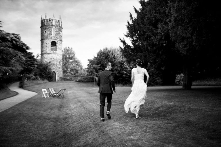 Couple run away from camera in the gardens at goldney house towards the tower, photo is in black and white