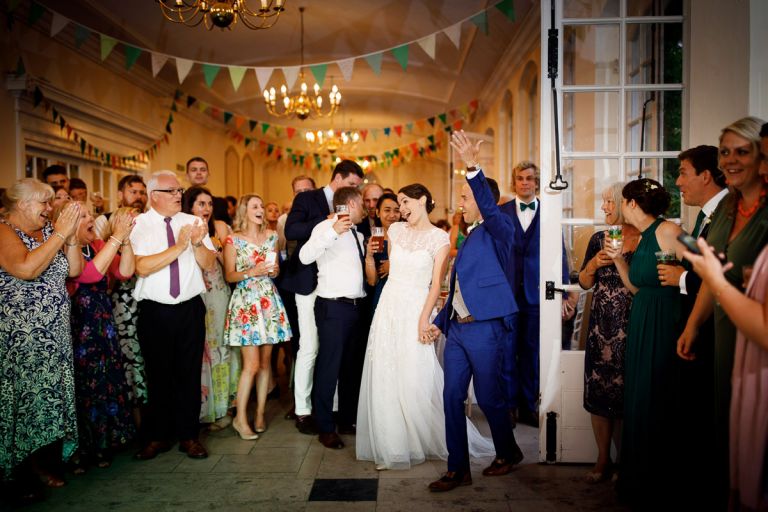 Guests clap and cheer the couple as they enter for their first dance in the orangery 