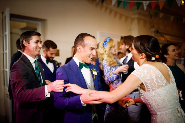bride, groom and guest play fight during dancing at their wedding