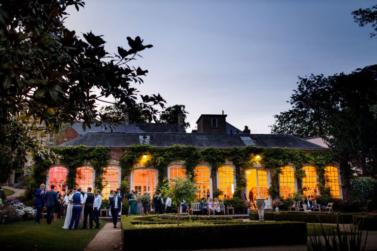 Outside wedding at the orangery at goldney hall in clifton, bristol. It's the evening and guests are outside. 
