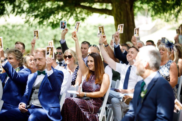 Guests hold up images as they play the mr and mrs game during the humanist ceremony at goldney hall