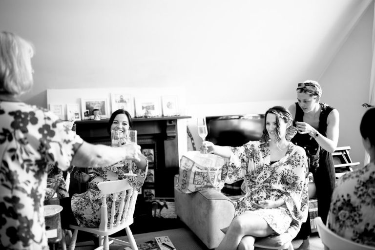 bride and bridesmaids toast with champagne before wedding at goldney hall