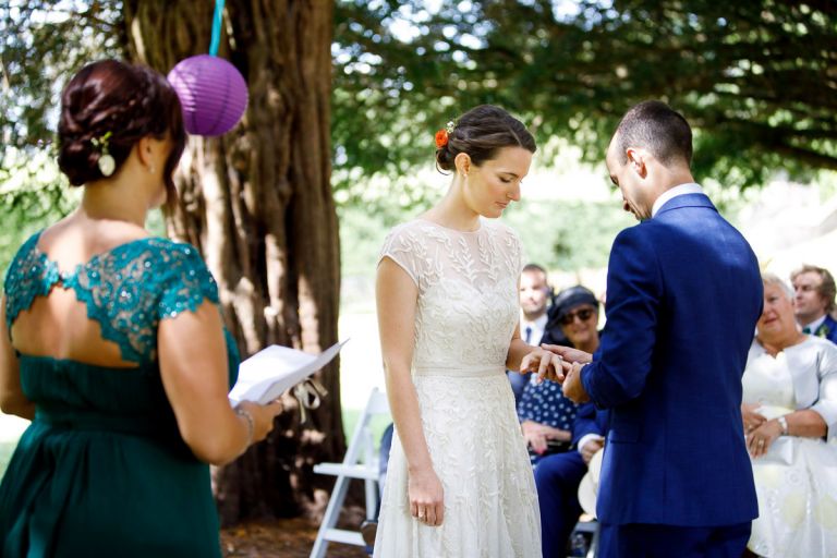 groom places wedding ring on her finger during outdoor wedding ceremony bristol