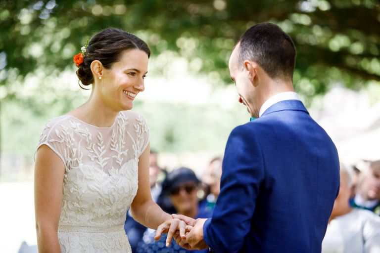 bride smiles at groom as he places the ring on her finger during outdoor wedding ceremony in clifton bristol