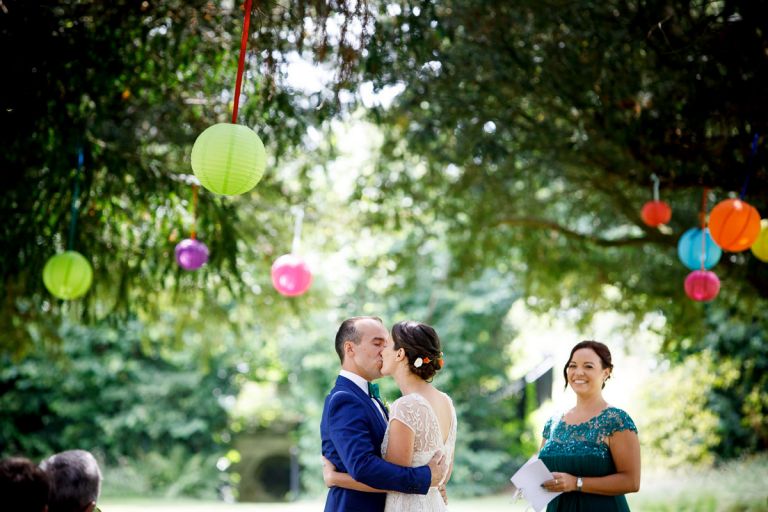 Couple share their first kiss under the trees and lanterns in the garden at goldney hall