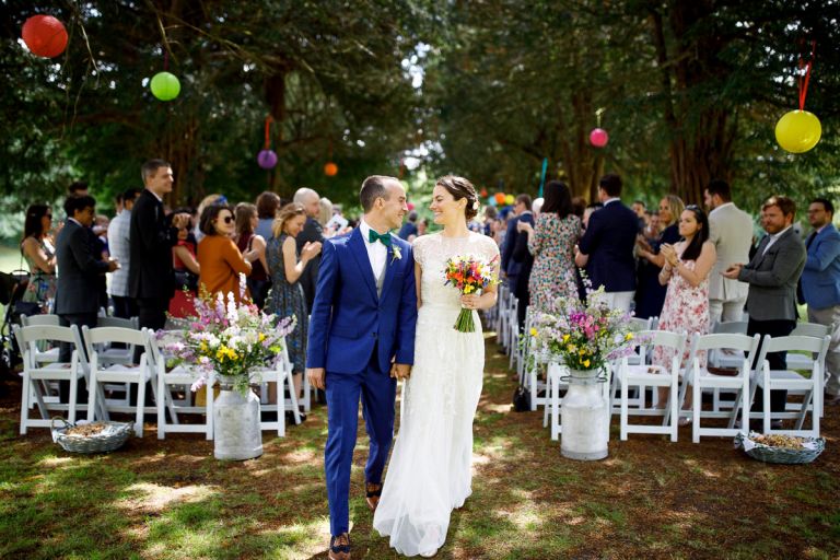 couple grin at each other as they walk up the aisle after their outside wedding ceremony bristol