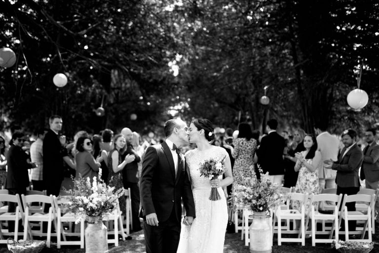 black and white photo of couple kissing as they walk back up their aisle outside in the gardens of goldney hall in clifton, bristol
