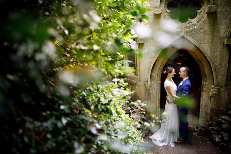 Couple in the doorway of the grotto in the gardens of goldney hall with foliage in the foreground