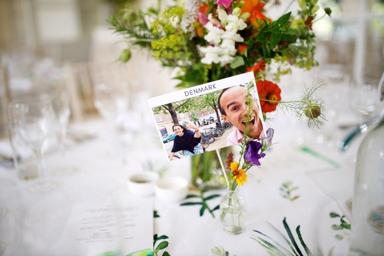 A table name card with the word Denmark on it and a photo of the couple after they just got engaged as part of the wedding decorations at the orangery at goldney hall clifton