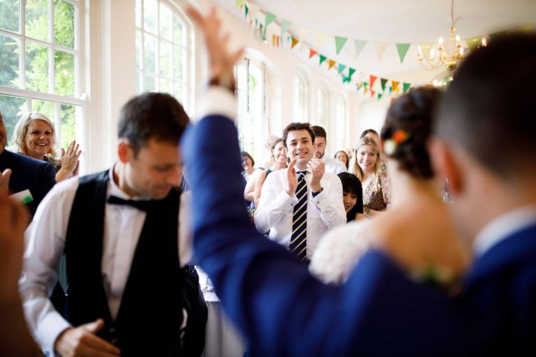 Guests clap the bride and groom as they enter the orangery for their wedding at goldney hall