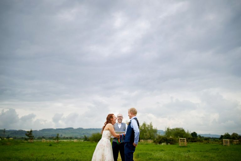 Bride, groom and celebrant laugh at inside joke during a handfasting at their ceremony