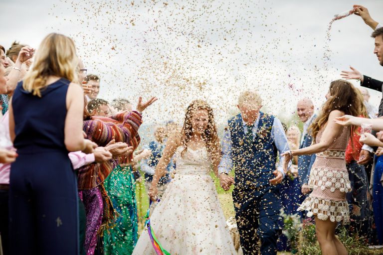 So much confetti is thrown at the couple that you can barely see them. 