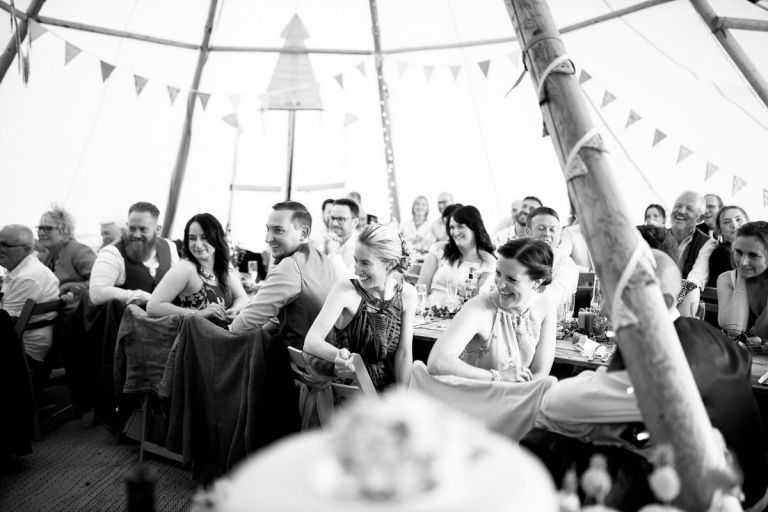 Guests laugh at wedding speech inside wedding tipi