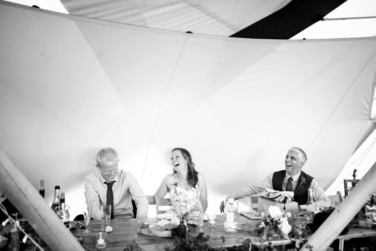 Couple and brides dad laugh at bestmans speech