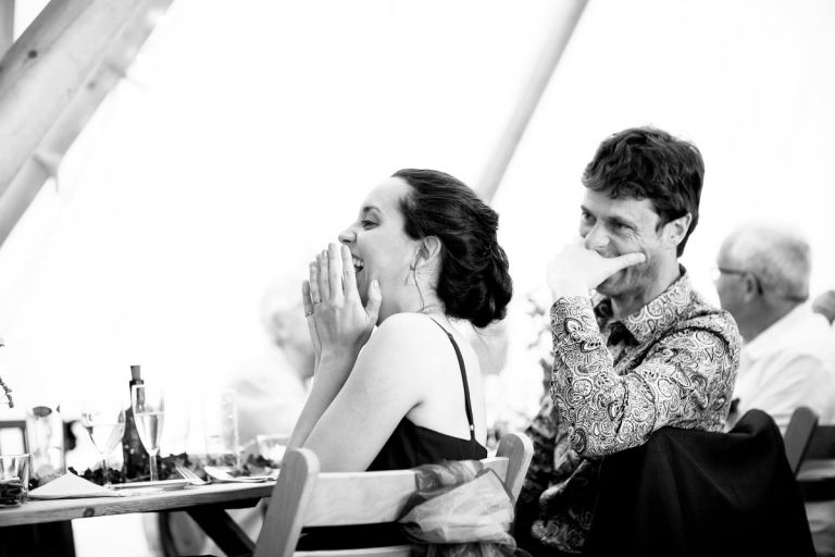 bridesmaid laughs with her hands to her face in disbelief during the bestmans speeches