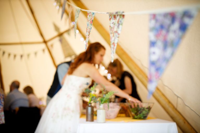Focus is on floral bunting and blurred out in the background is bride helping herself to the wedding food, sets the scene for the laid back meal they are having. 