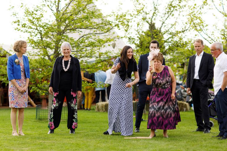 Guests play a game at wedding reception, lady is taking her aim very seriously