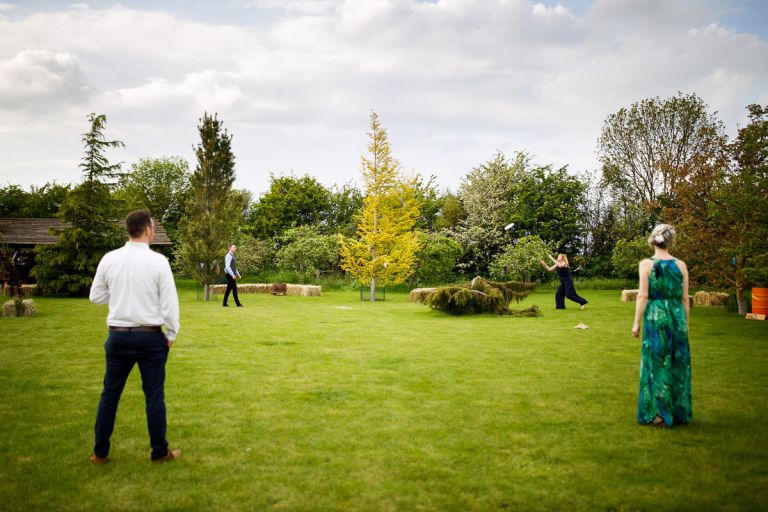 Four people play frisbee outside at wedding reception