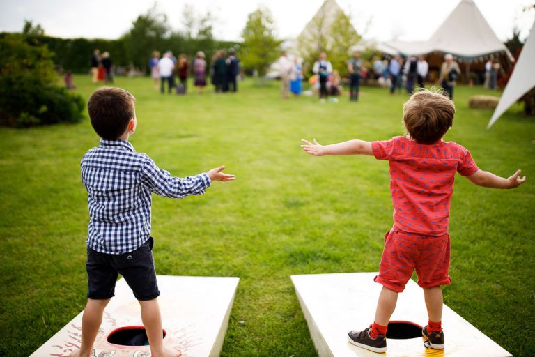 two kids wait for balls to be thrown towards them during a game at the wedding