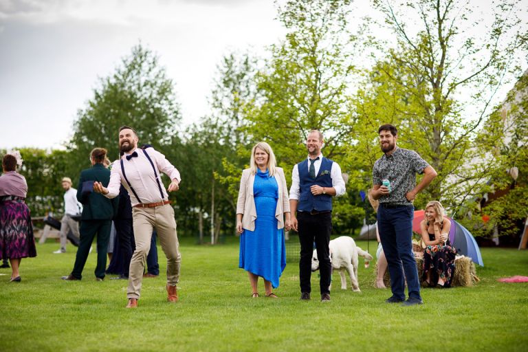 Group of guests watch a man play a game at the wedding