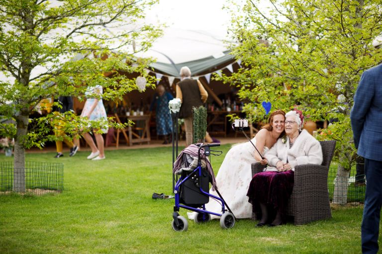 Bride poses for selfie with her grandma using selfie stick. 