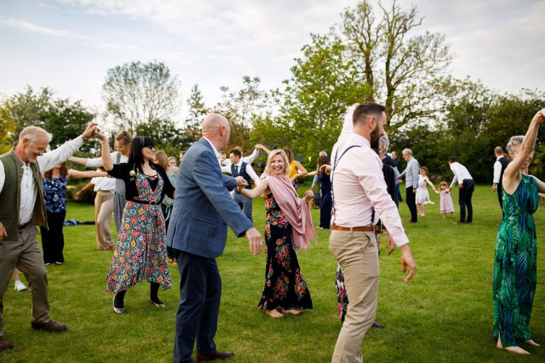 Guest smiles at her partner surrounded by other pairs as part of the ceilidh