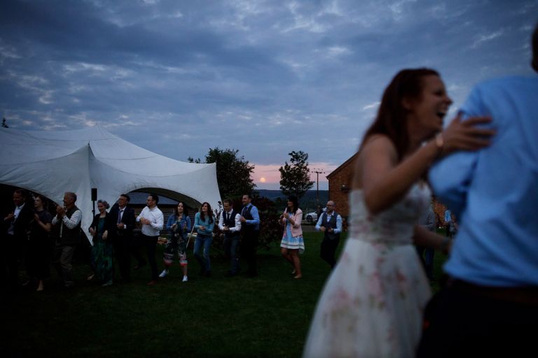 while guests dance and wedding couple laugh we can see the red moon rising in the background