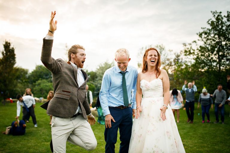 Couple laugh as guests jumps at them during outside dancing