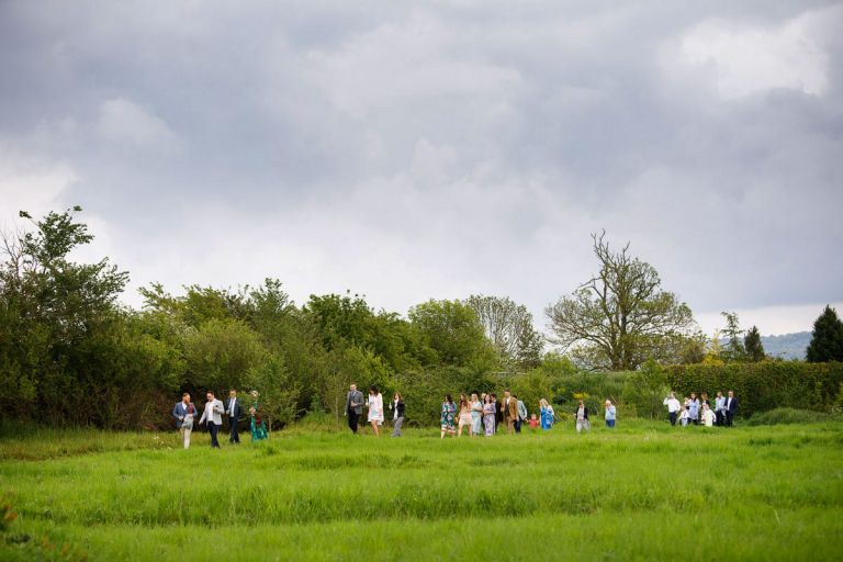 Guests walk along the edge of a field to get to the ceremony site for the outdoor wedding ceremony