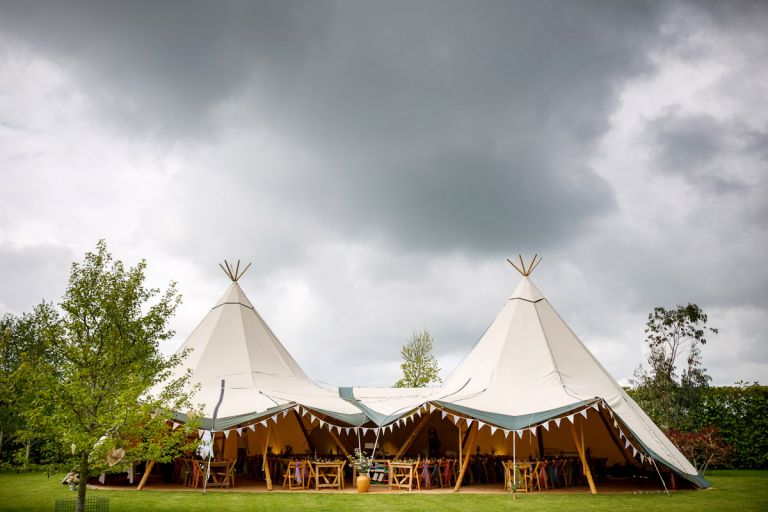 Tipi decorated for a wedding reception with lots of bunting and colourful scarfs. 