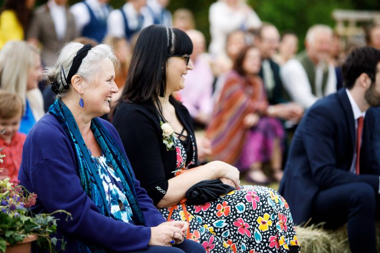 Guests laugh during wedding ceremony outside