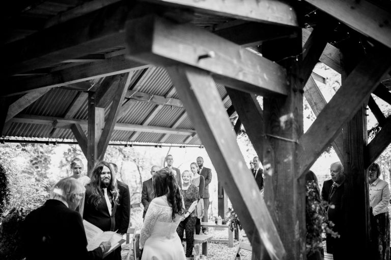 Couple stand during their ceremony under the wooden structure at arnos vale