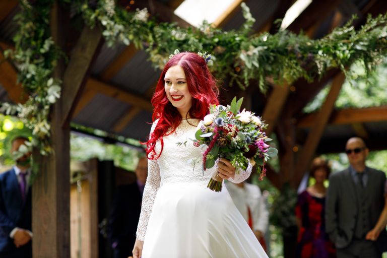 bride with red hair smiles and holds bouquet. 