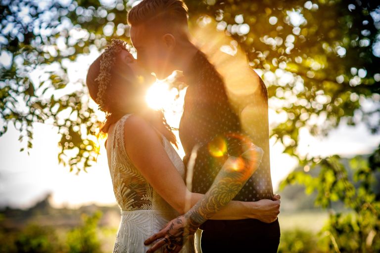 Beautiful sun flare as couple kiss in evening golden light