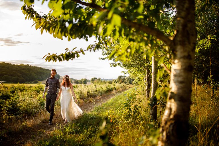 The Over Barn couple walk in trees in the evening light