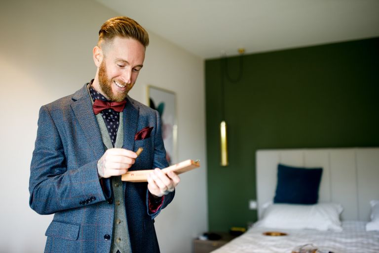 Groom looks at cigars in a box before wedding